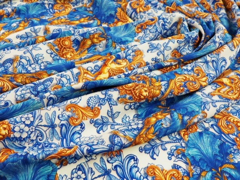 jedwab w niebieskie irysy i ornamenty raz złote słońca i pegazy na bialym tle