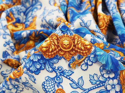 jedwab w niebieskie irysy i ornamenty raz złote słońca i pegazy na bialym tle